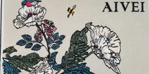 High-quality damask woven label featuring intricate floral embroidery design and smooth text.