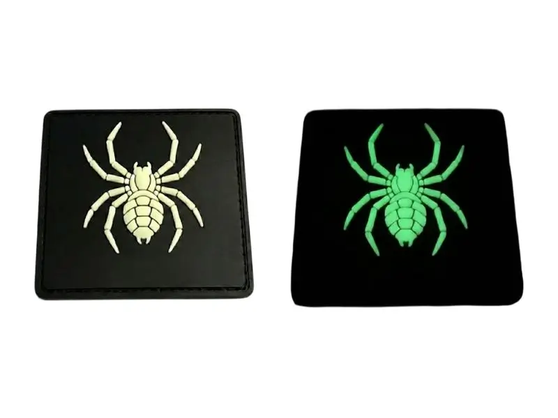 Side-by-side comparison of a custom PVC spider patch in normal light versus glowing phosphorescent green in the dark.