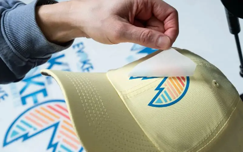 Close-up of the heat-press application process for a custom printed hat patch, ensuring a seamless and permanent bond