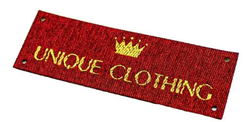 Red custom woven clothing label with distinct gold typography and crown logo.