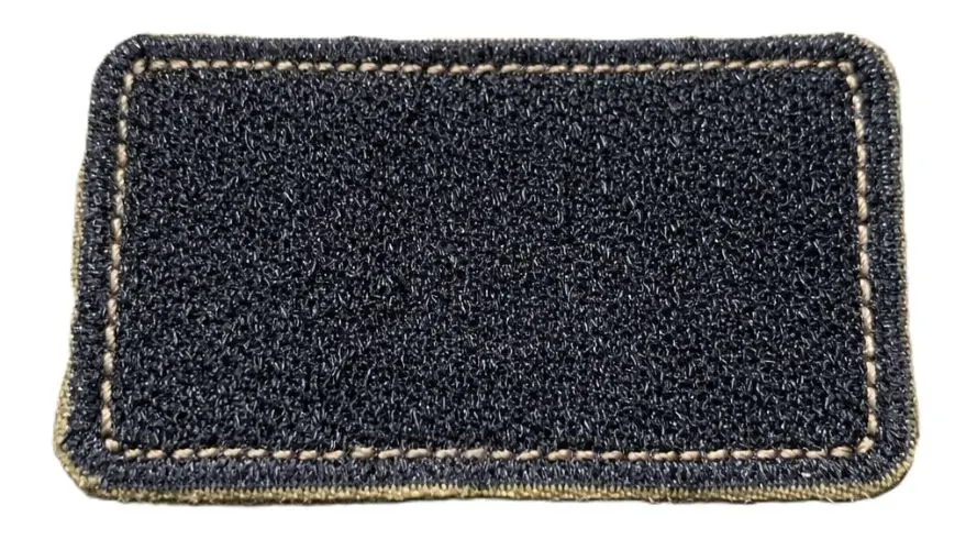 Close-up of the back of a military patch showing durable black Velcro hook backing stitched to the border.