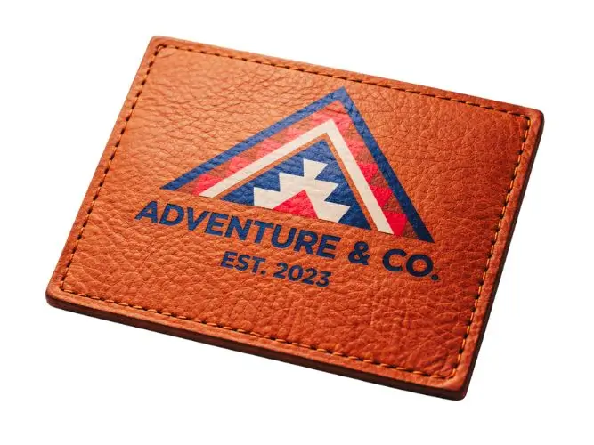 Full-color custom UV printed leather patch featuring a vibrant geometric logo design on textured cognac hide.
